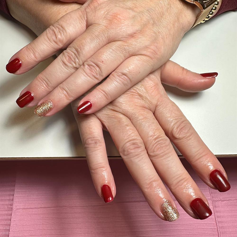 Korte rode nagels met een gouden glitteraccentnagel